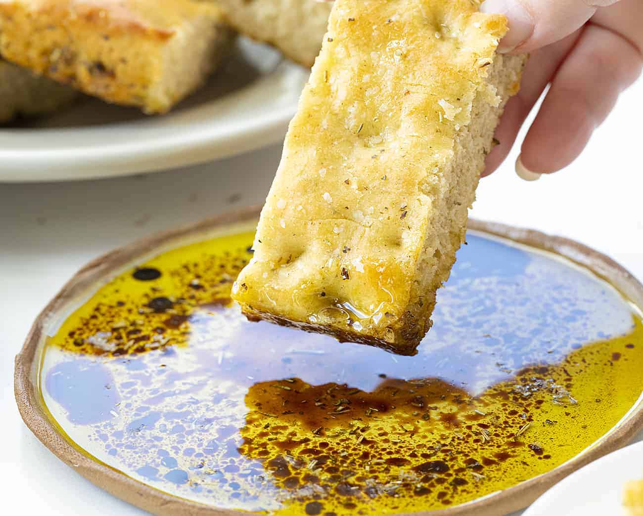Dipping Piece of Focaccia Bread into Oil and Balsamic Vinegar
