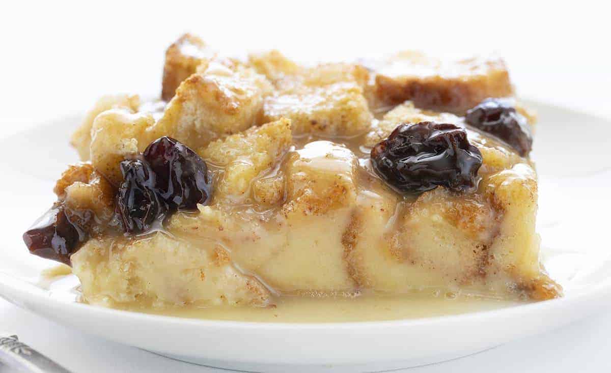 Very Close Piece of Old Fashioned Bread Pudding with Raisins on White Plate