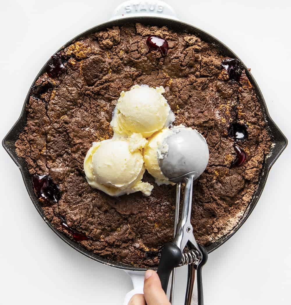 Fagylalt hozzáadása a fehér serpenyőben sült csokoládés meggyes Dump Cake recepthez