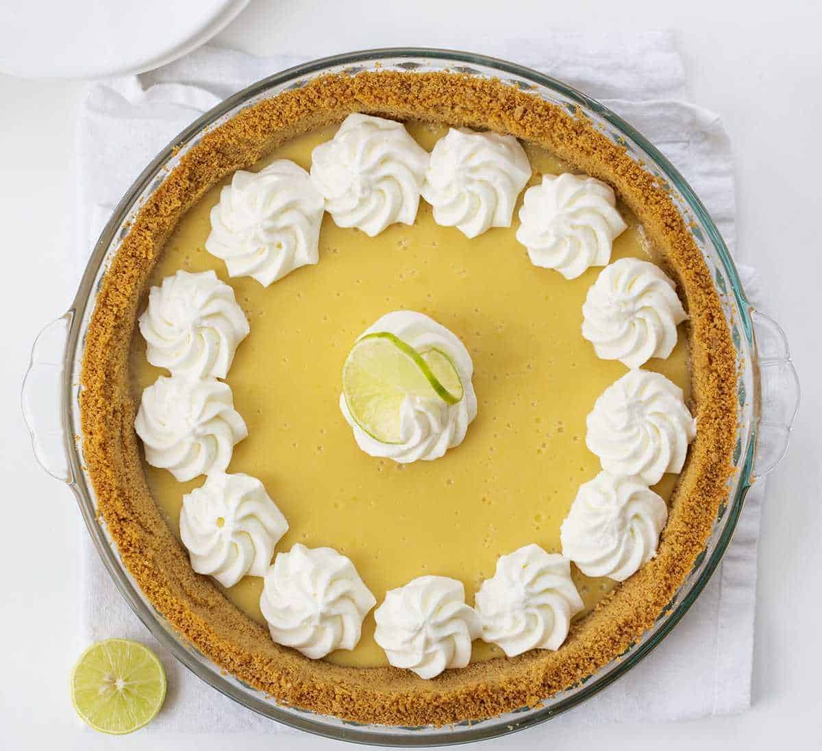 Overhead View of Key Lime Pie with Whipped Cream Dollops and a sliced key lime next to it