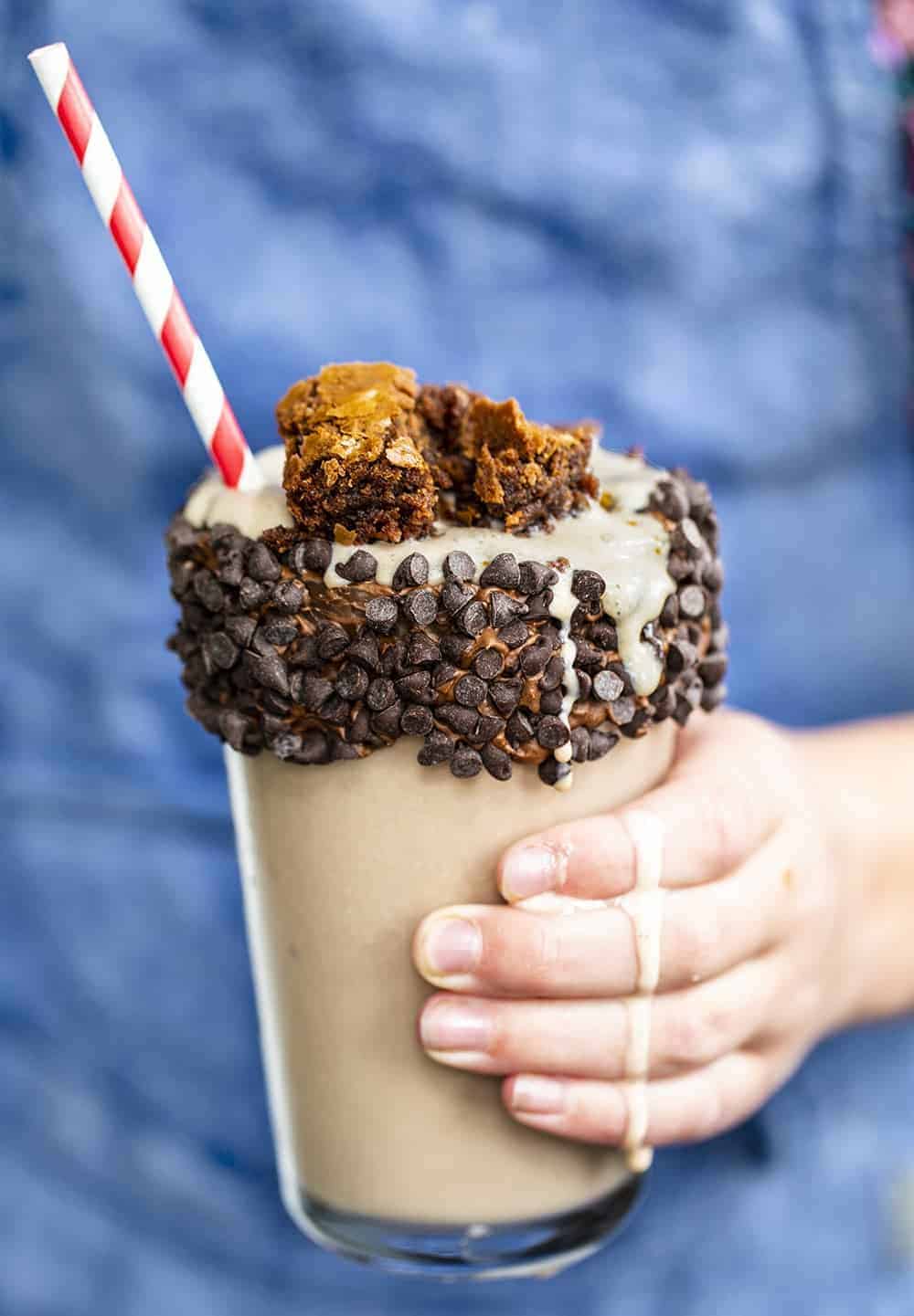 Hand Holding the Ultimate Chocolate Milkshake with Brownies on Top