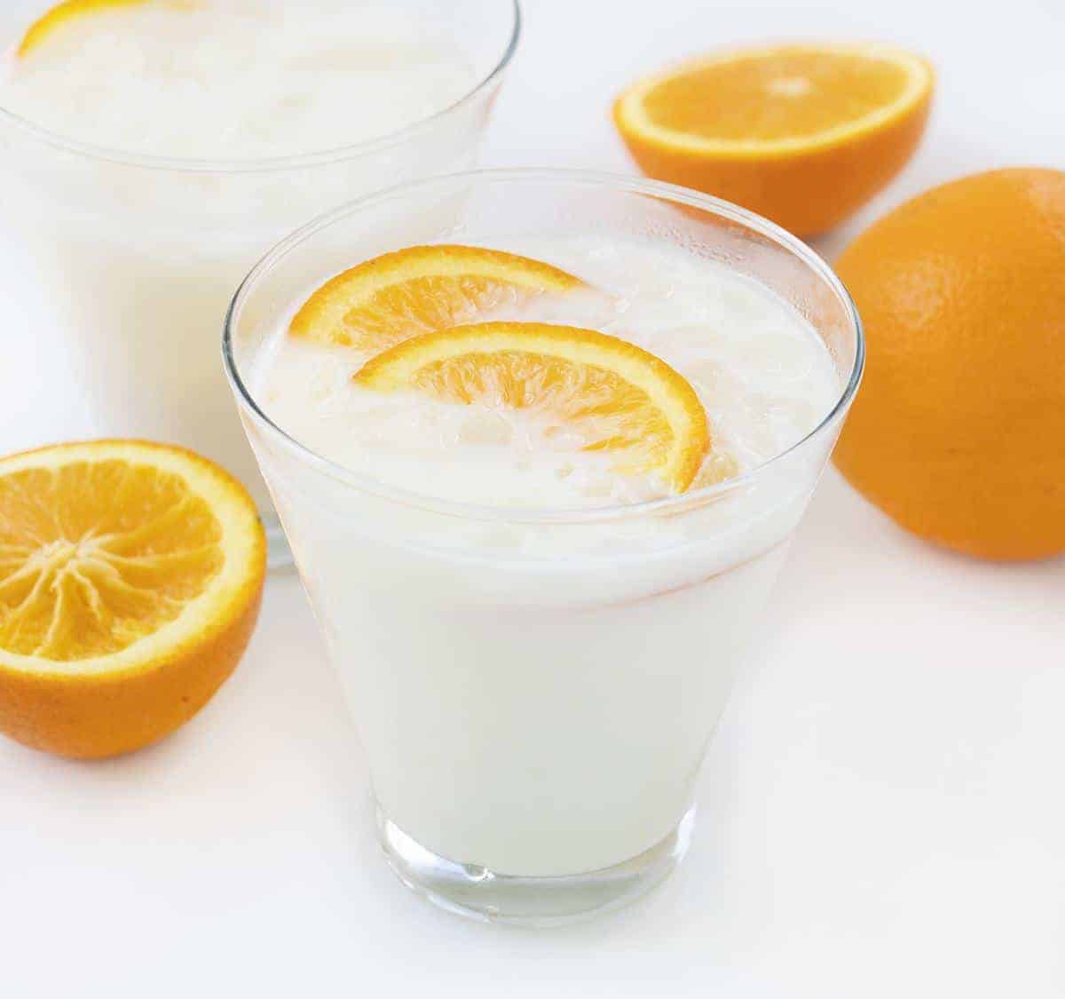 Iced Orange Creamsicle Drink in Cocktails Glass with Oranges Around It