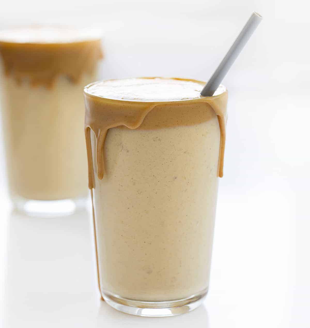 Peanut Butter Banana Smoothie in a Glass with a Grey Plastic Straw