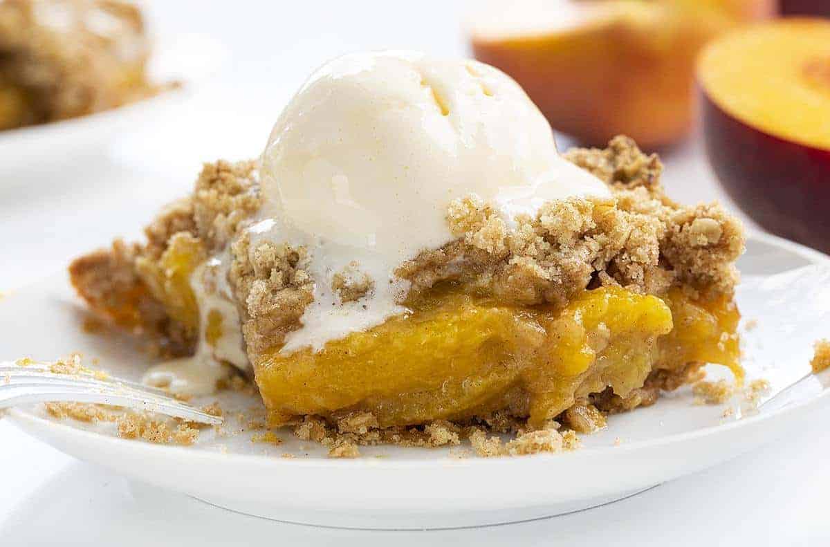 Piece of Peach Crisp with Bite Missing and Fork Resting on Plate