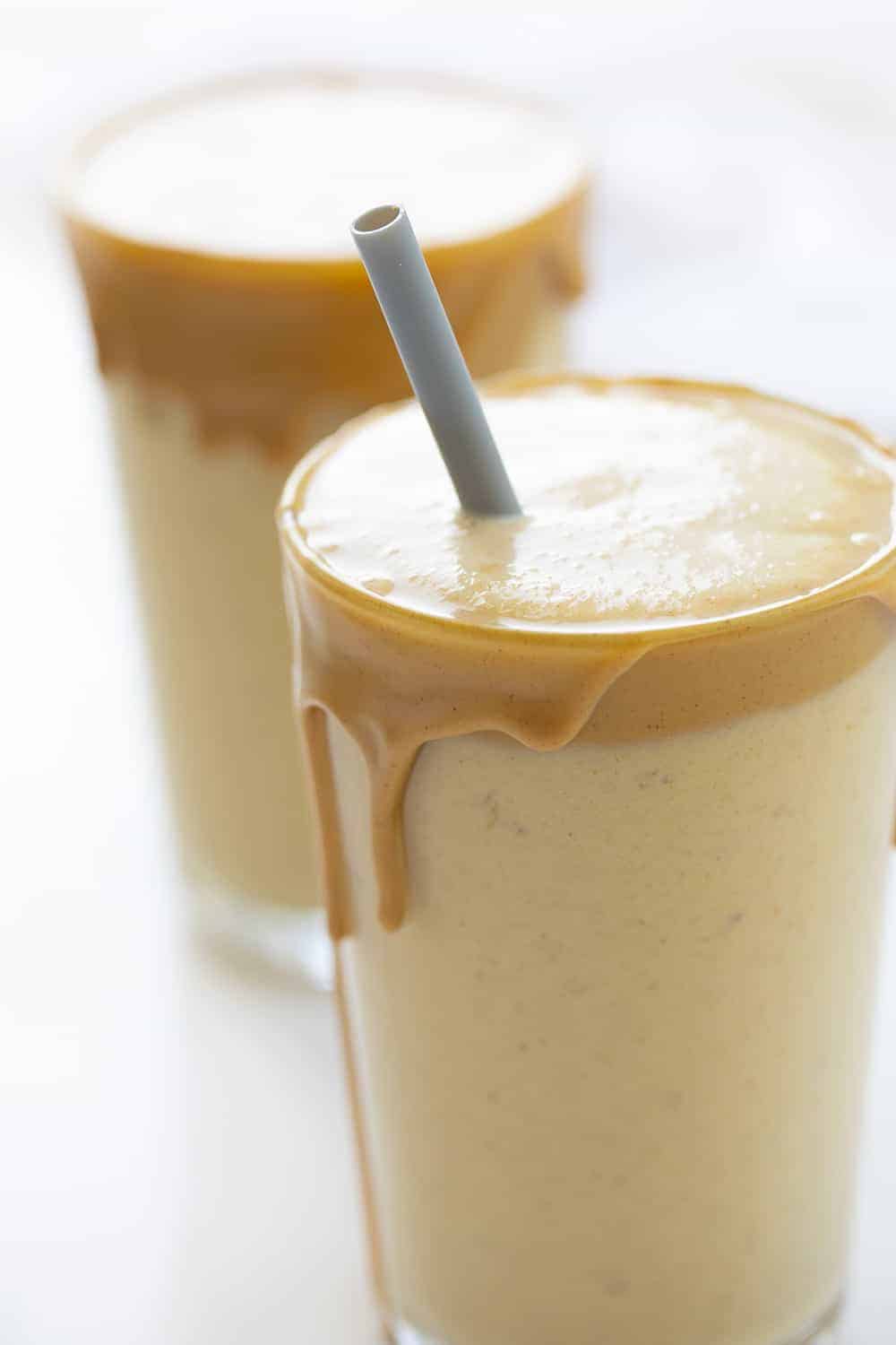 Two Glasses of Peanut Butter Banana Smoothies with Grey Plastic Straw