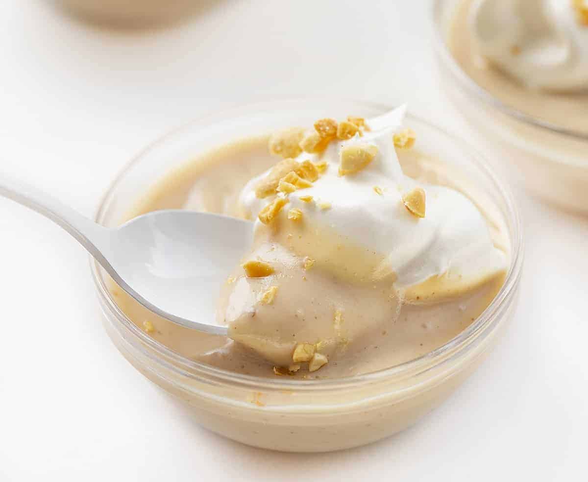Spoon Taking Bite of Homemade Peanut Butter Pudding with Whipped Topping and Peanuts