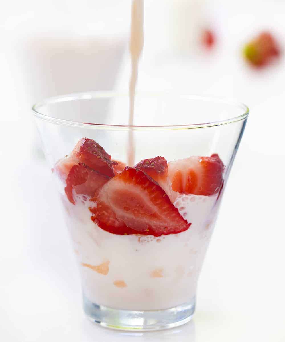 Pouring Milk into Strawberry's and Cream Milk Glass with Strawberries and Ice
