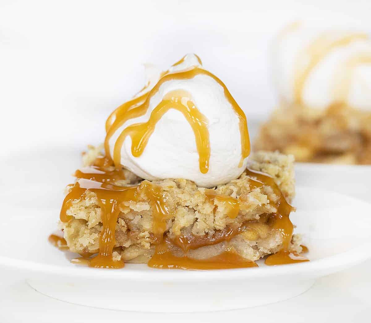 One Piece of Oatmeal Caramel Apple Bar on White Plate with Whipped Cream and Caramel