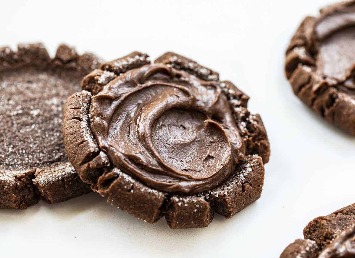 Chocolate Sugar Cookies with Chocolate Frosting on White Counter with Other Cookies Around it
