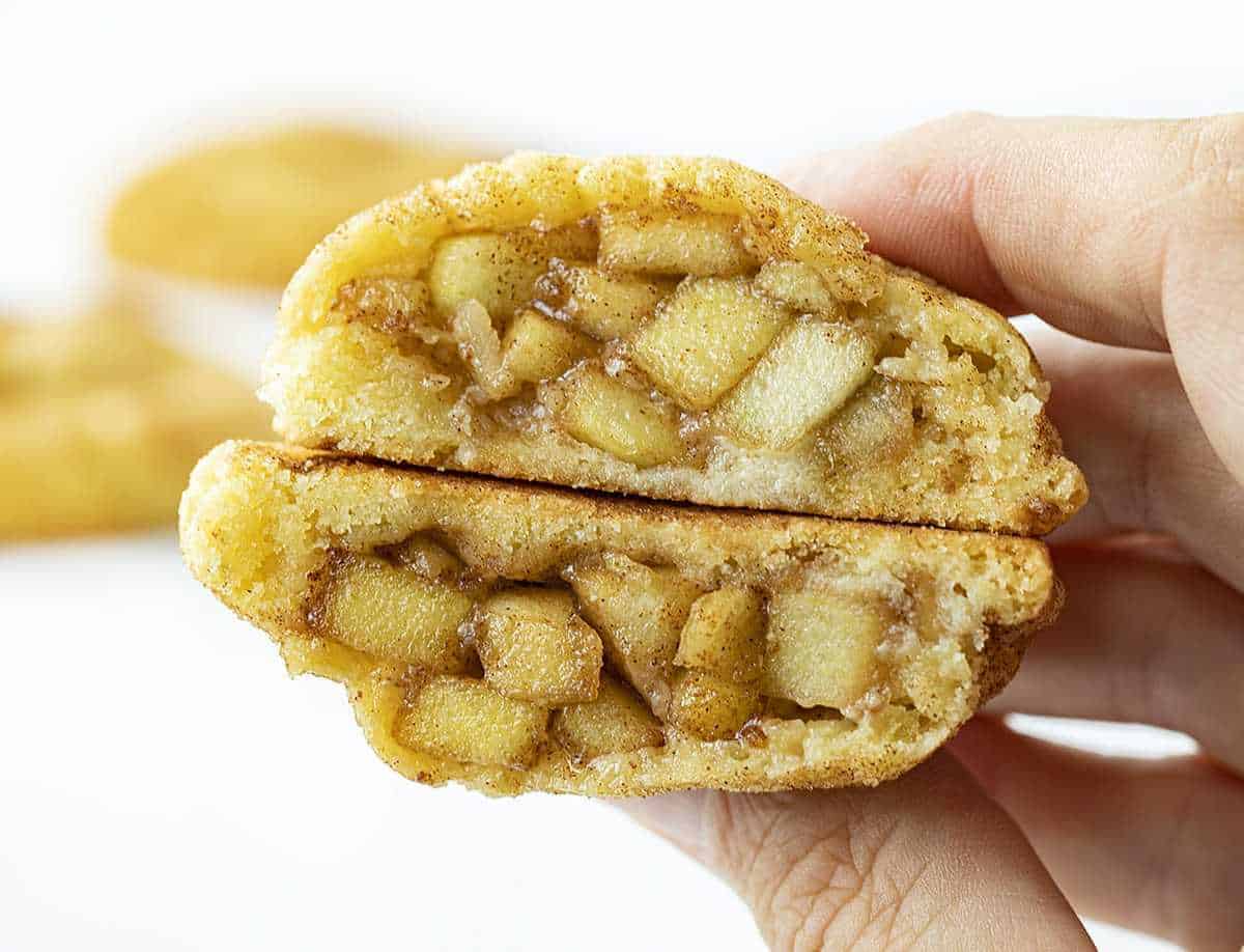 Ruka držící jablečný koláč Snickerdoodles rozříznutá napůl ukazuje vnitřek