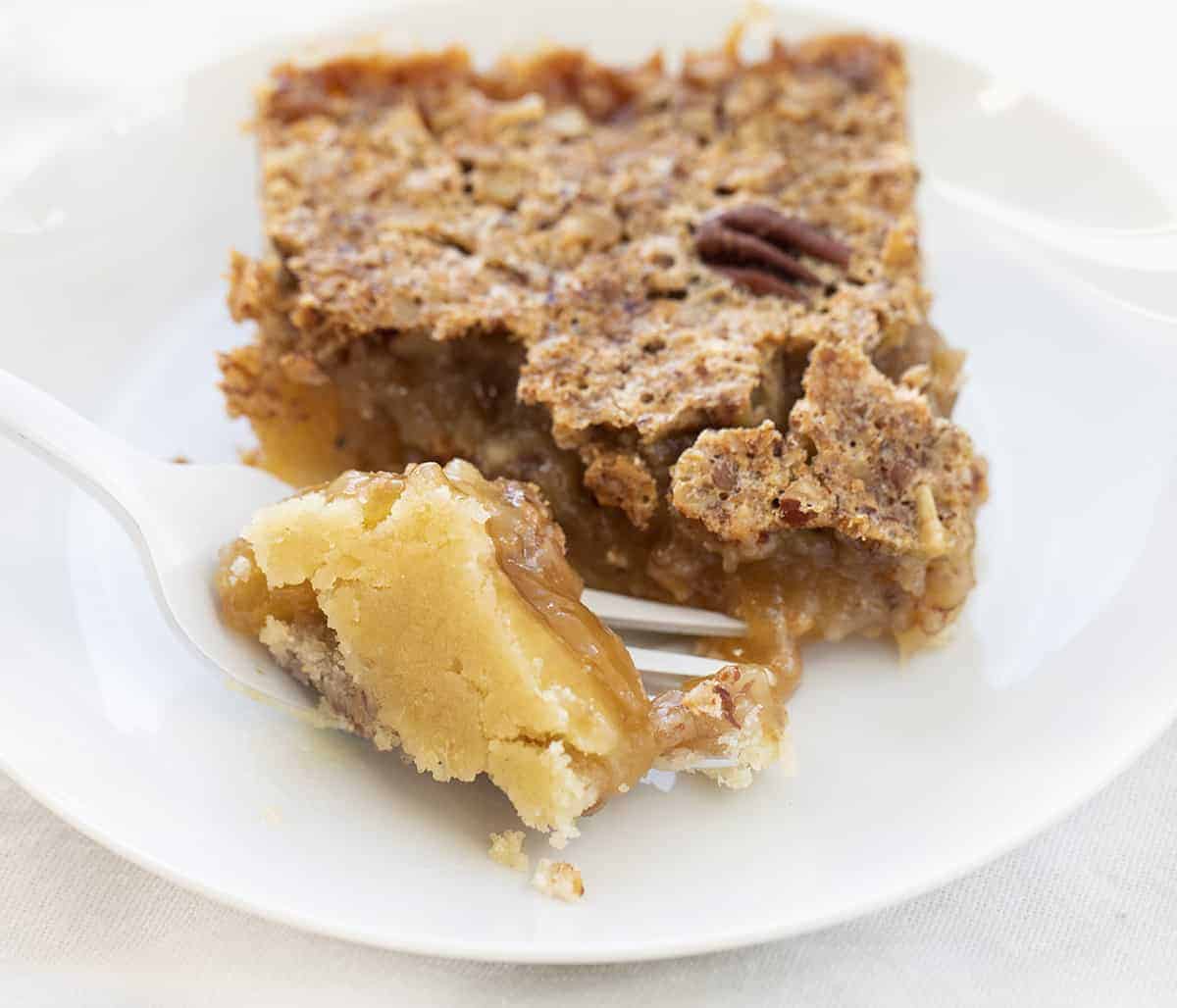 One Pecan Pie Bar with Fork Holding Piece Showing Crust