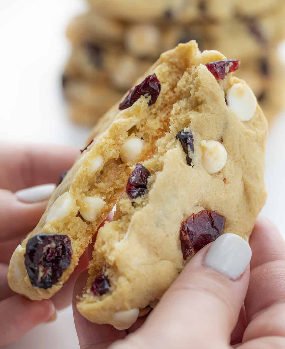 Hands Breaking Soft Batch White Chocolate Cranberry Cookie in Half