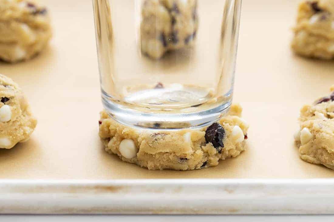 Glass Pressing Down Soft Batch White Chocolate Cranberry Cookie Batter