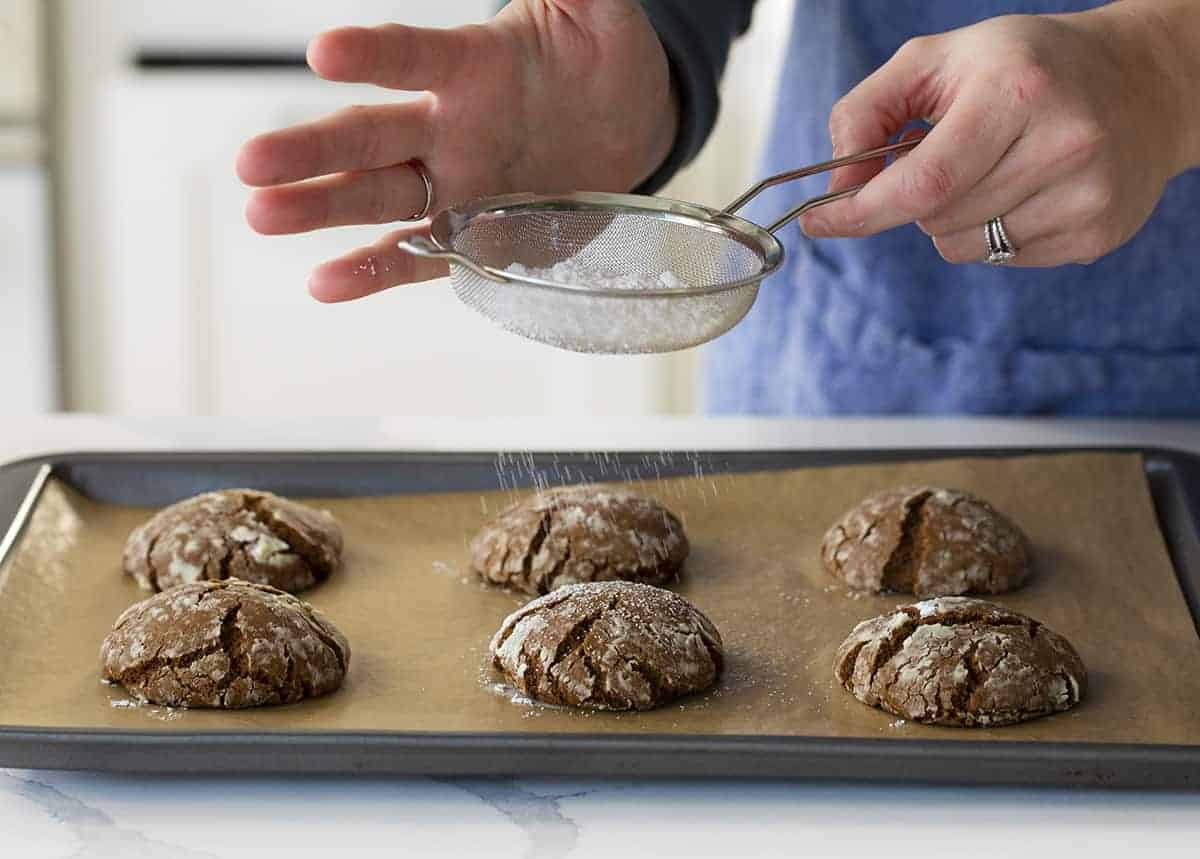 Sprinkling Confectioners Sugar over Gingerbread Crinkle Cookies