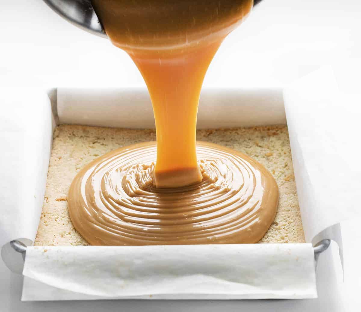 Pouring Caramel onto Shortbread for Millionaire Bars 