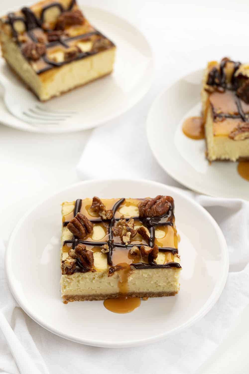 Pieces of Turtle Cheesecake Bars on Plates