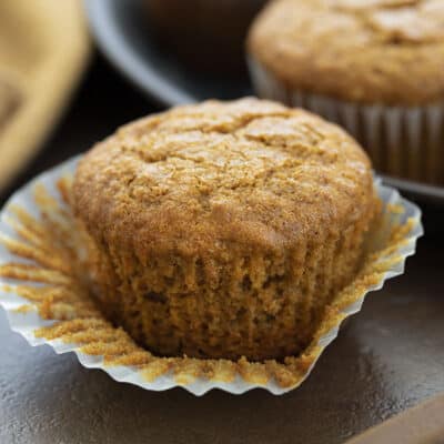 One bran muffin with the wrapper peeled back showing tender crumb.