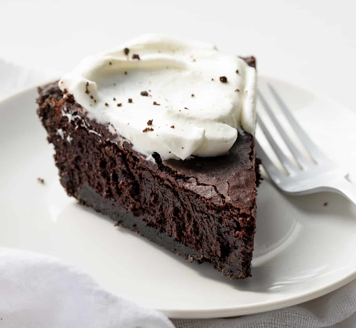 Piece of Brownie Pie on a White Plate with Whipped Cream.