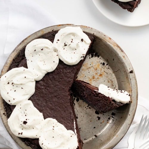 Pie Pan with Brownie Pie in it and a Few Pieces Removed on a White Counter.