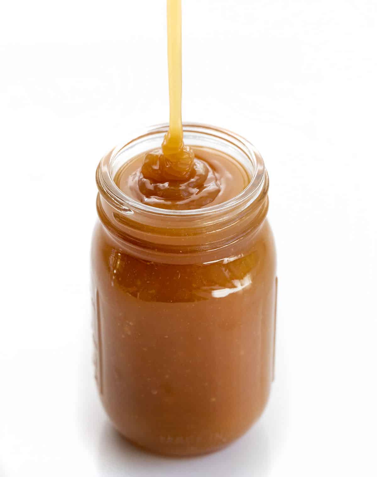 Caramel Sauce is a versatile and flavorful condiment that can be added to many recipes and desserts for added sweetness. Homemade Caramel, Dry Method Caramel, 3 ingredient Caramel, Easy Caramel Sauce, The Best Caramel Sauce, recipes, dessert,i am baker, iambaker Pouring Caramel Into Jar