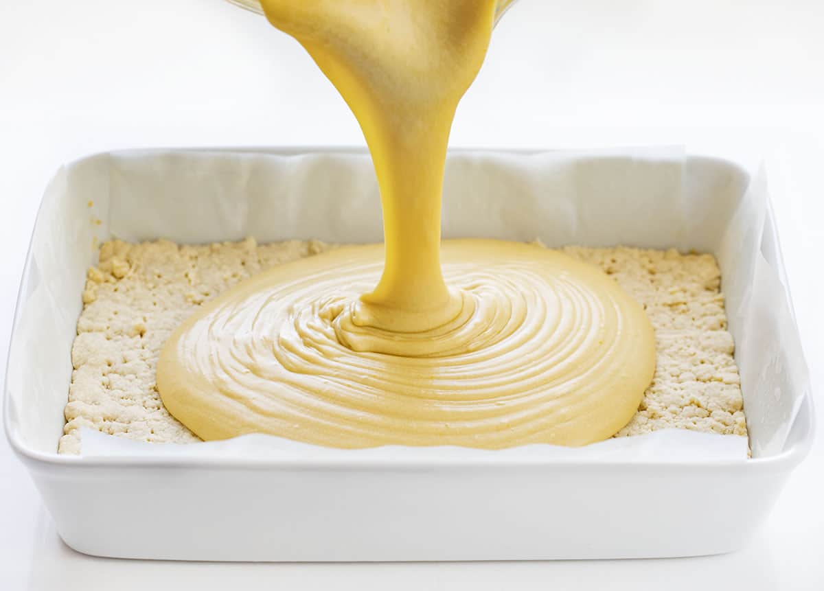 Pouring Ooey Gooey Butter Batter onto Crust in white pan