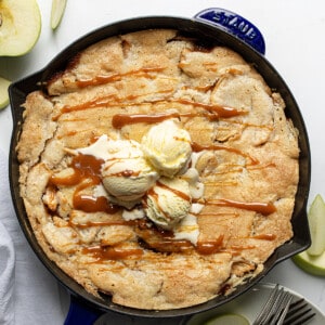 Skillet of Swedish Apple Pie on a White Table With Cut Apples From Overhead.