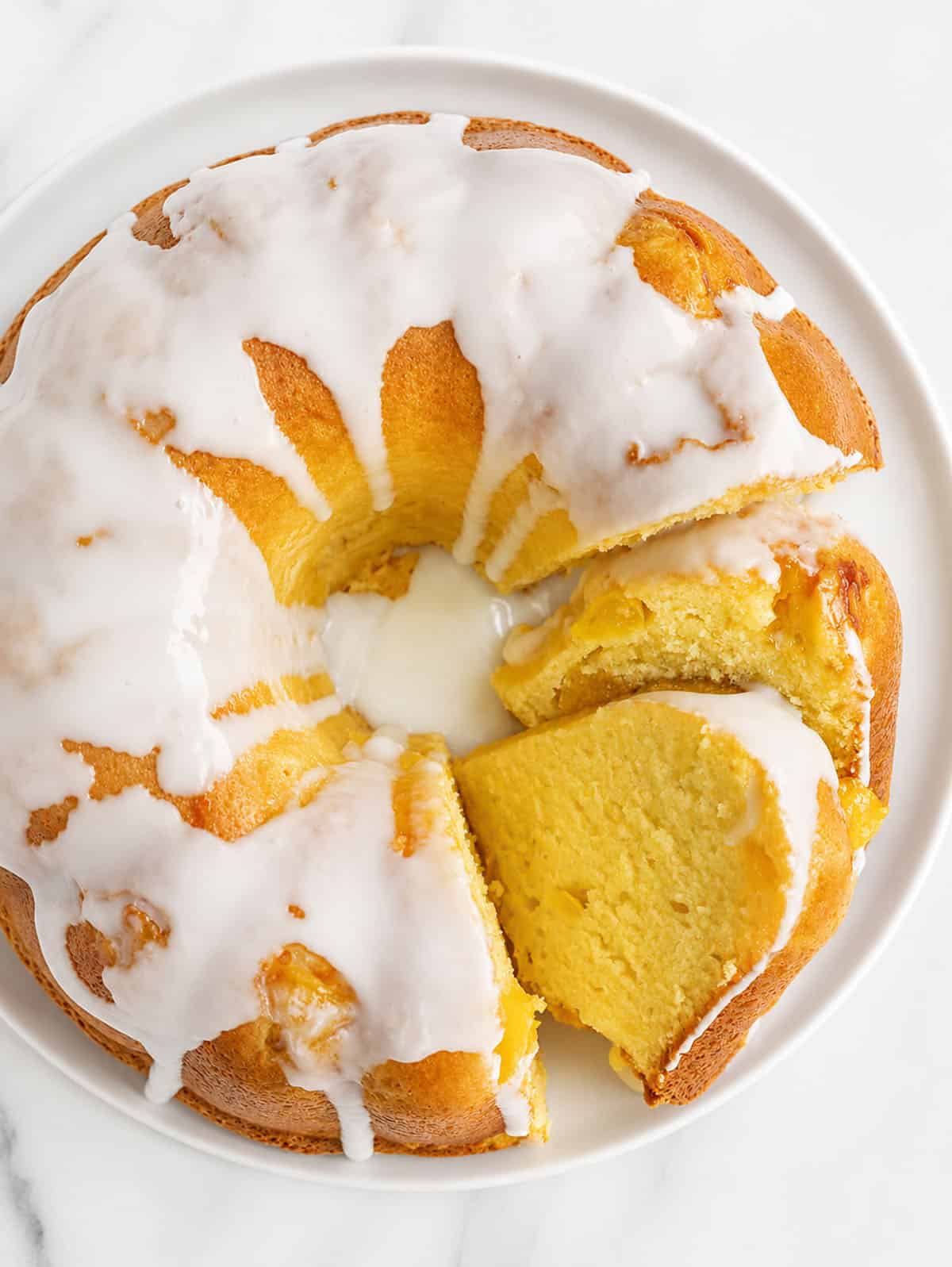 Peach Pound Cake on a white platter with a couple of pieces cut and laying on their side from overhead.