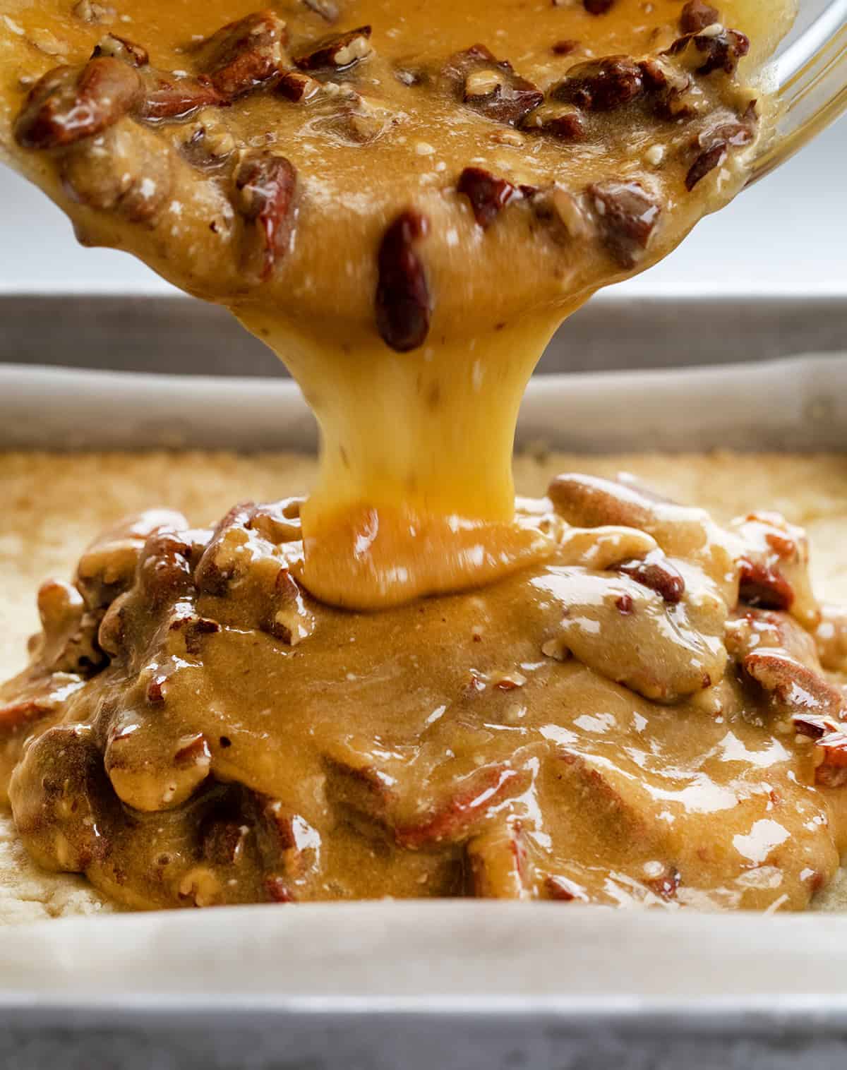 Pouring pecan pie filling over shortbread crust.