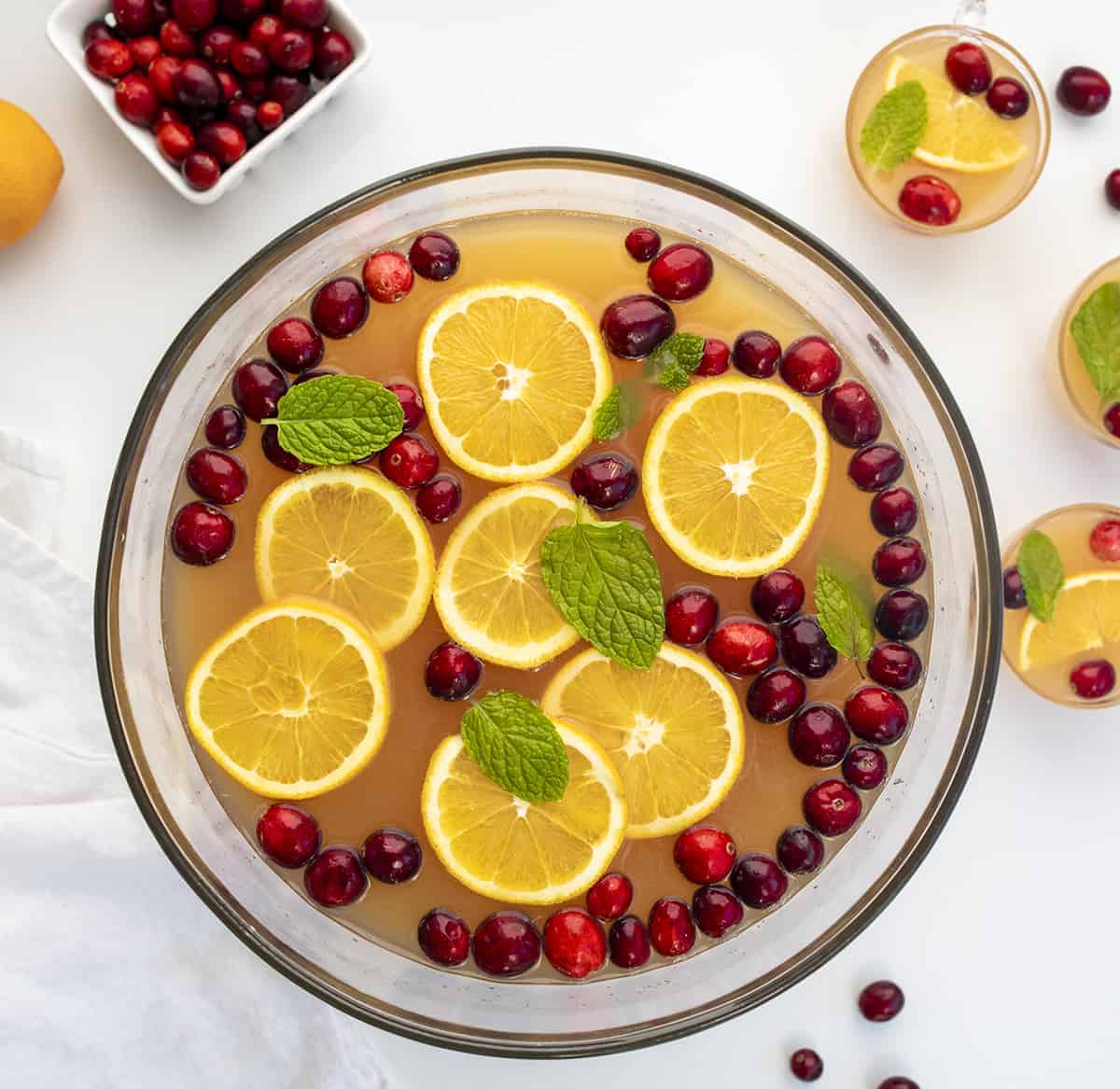 Overhead of glass bowl filled with Christmas Punch and several serving glasses.   Christmas Menu, Menu Planning, menu ideas, holiday menu, holiday menu planning, holiday menu ideas, Christmas meal, hosting Christmas, how to host Christmas,  i am baker, iambaker, christmas punch, christmas drinks, cranberry orange punch, cranberry punch, orange punch, holiday punch