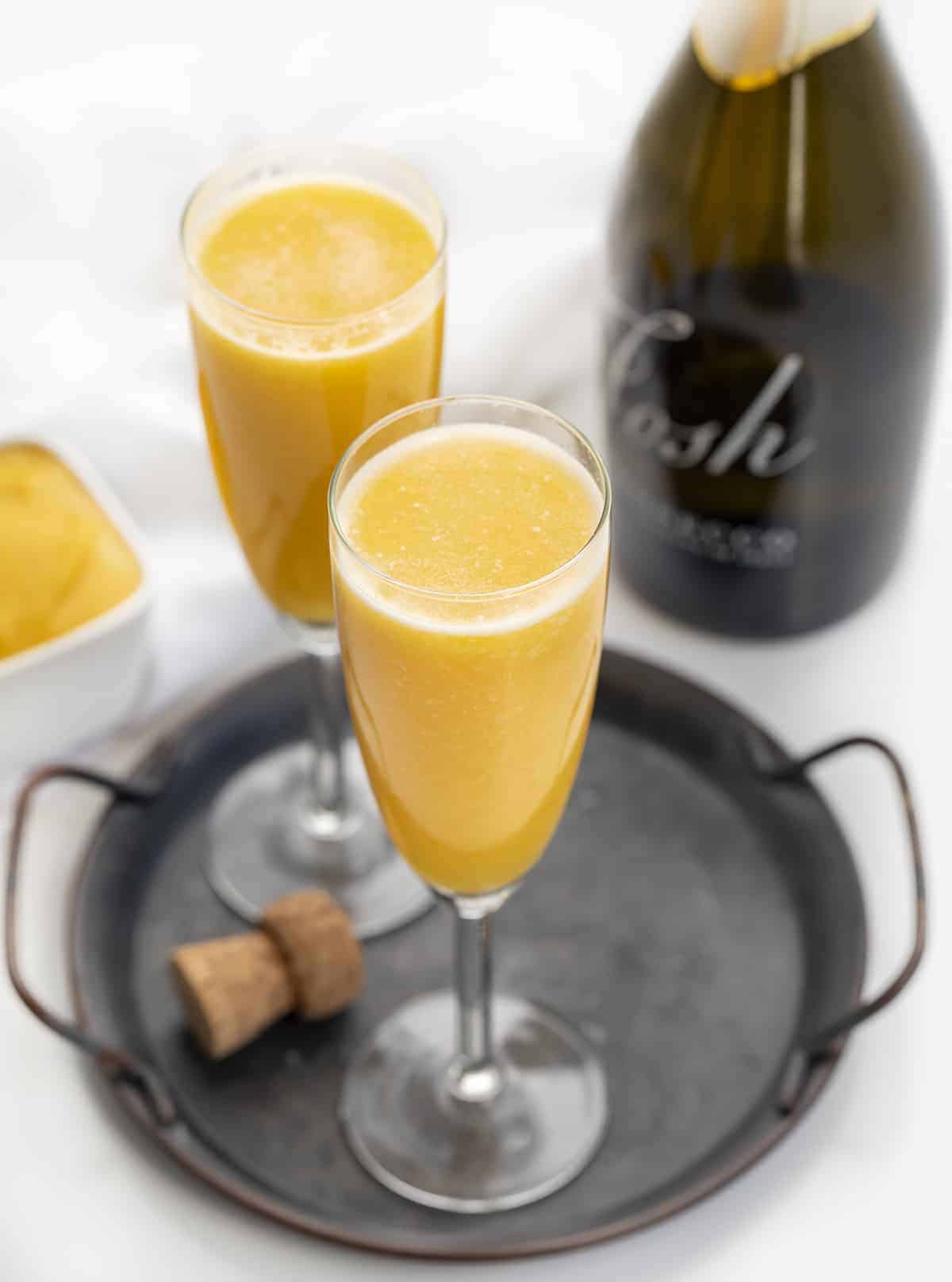 Glasses of Peach Bellini Cocktail with Prosecco Bottle.