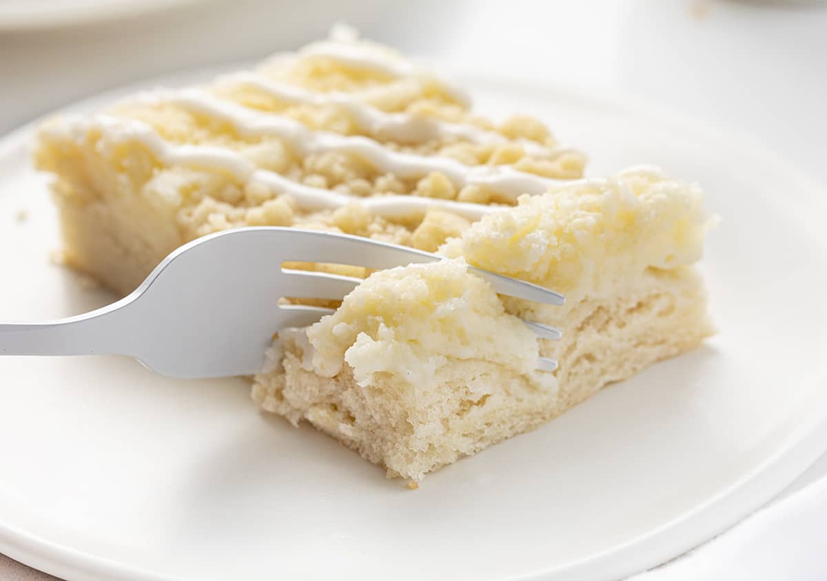 Fork Taking Bite from Cream Cheese Sweet Bread on a White Plate