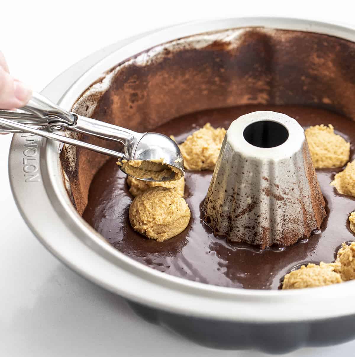 Adding Peanut Butter Filling to Chocolate Peanut Butter Bundt Cake Batter in Cocoa Lined Cake Pan