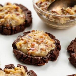 German Chocolate Cookies on a white table with german chocolate frosting in a bowl.