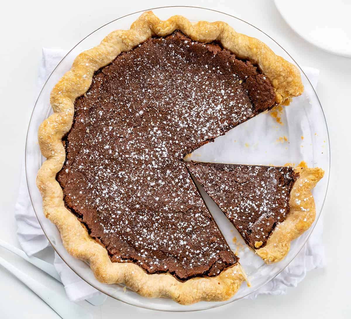 Overhead of a Chocolate Chess Pie with a Piece removed and Another Piece Cut