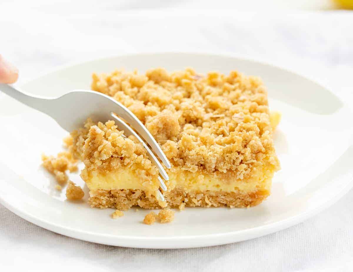 Fork Taking a Bite of Lemon Crumb Bar on a White Plate