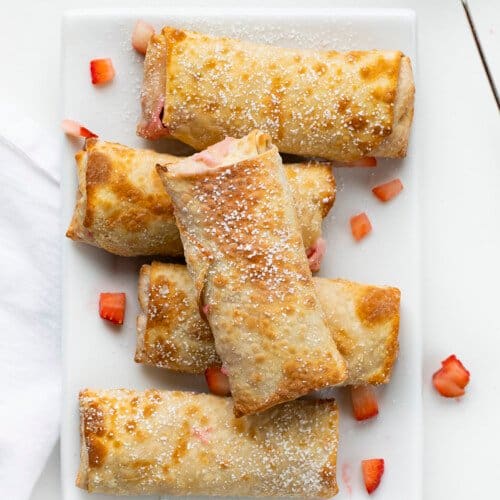 Strawberry Cheesecake Egg Rolls Stacked on a White Serving Plate From Overhead