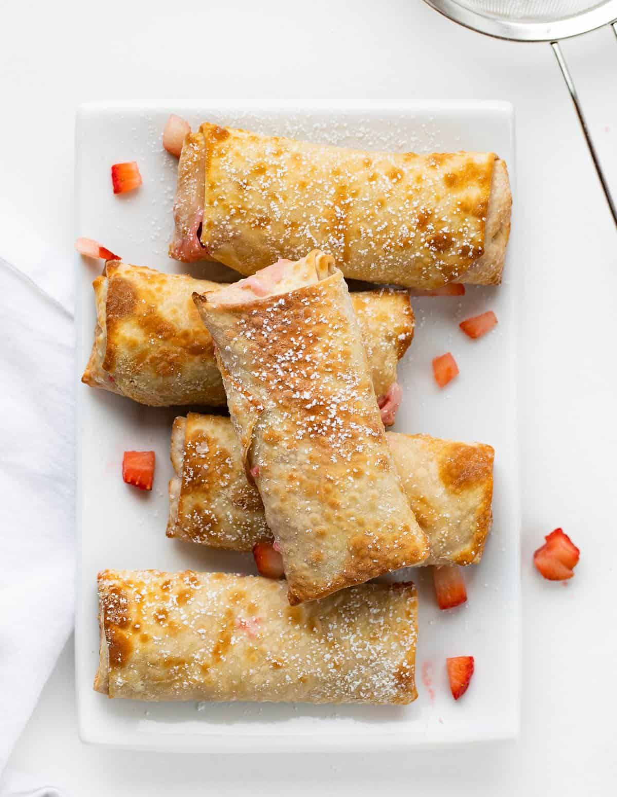 Strawberry Cheesecake Egg Rolls Stacked on a White Serving Plate From Overhead