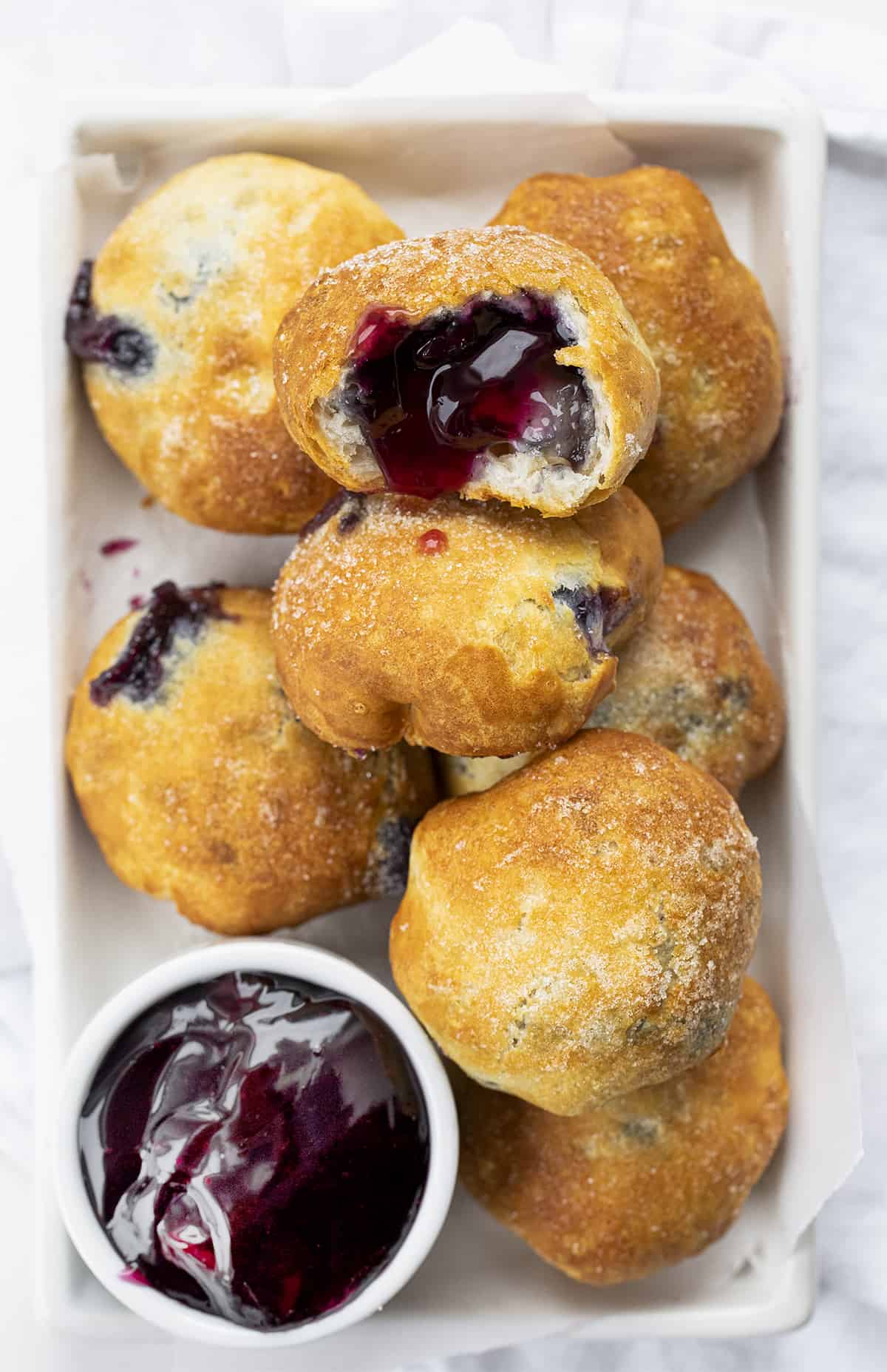 Tray of Blueberry Pie Bombs with One Cut Open. Breakfast, Blueberry Pie Bombs, Fruit Filled Hand Pies, Air Fryer Recipes, Blueberry Breakfast, Baked Blueberry Desserts, Dessert, Cherry Pie Bombs, Baked Pie Bombs, recipes, i am baker, iambaker