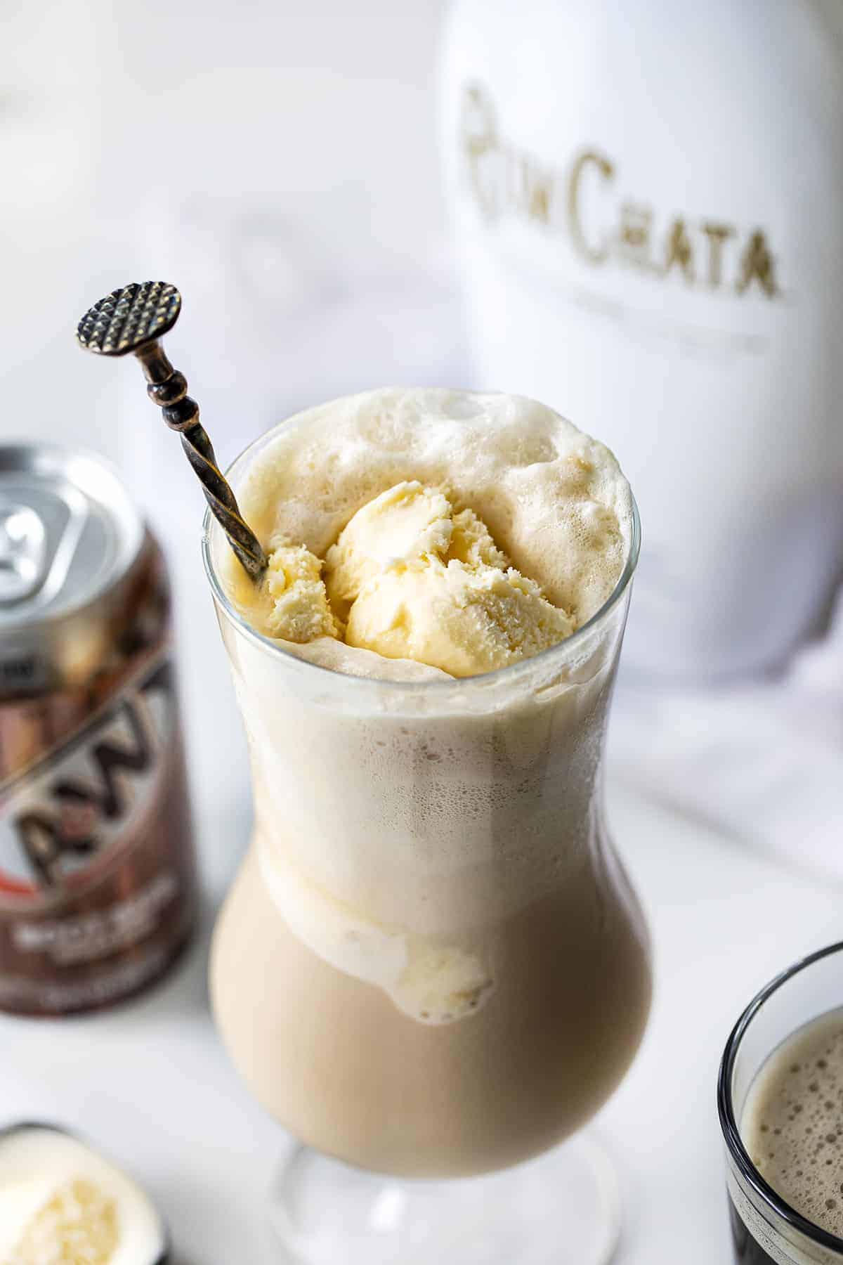 Dirty Root Beer Float - RumChata Root Beer Float in a Glass with RumChata Bottle and Root Beer Can in Background.