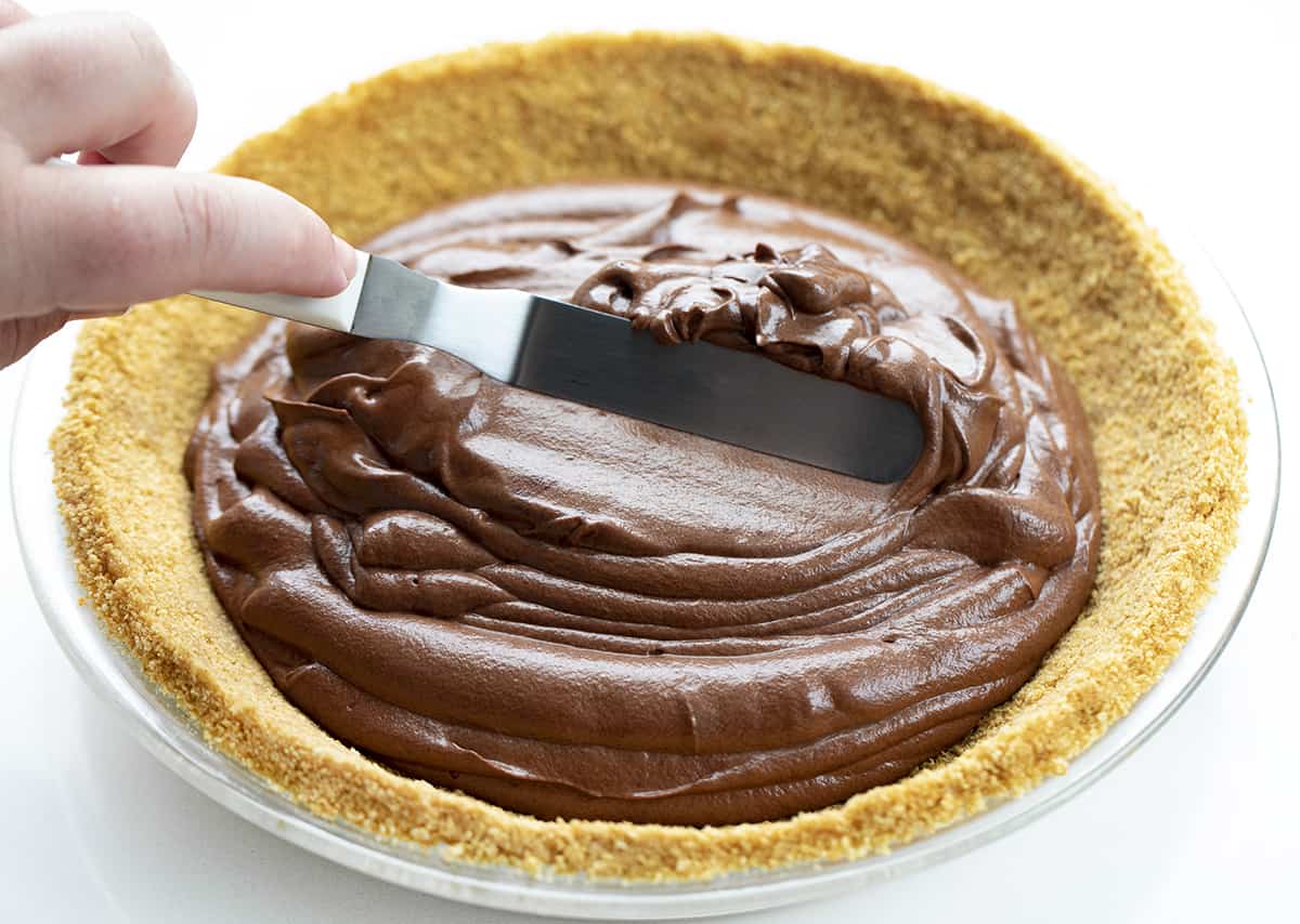 A small offset Spatula Smoothing out the Filling in a Chocolate Icebox Pie. Dessert, Pie, No Bake Pie, Chocolate Desserts, no Bake Chocolate Desserts, Summer Dessert, Dark Chocolate Dessert, What to Serve to Company for Dessert, recipes, chocolate, chocolate curls, Whipped Cream, i am baker, iambaker.