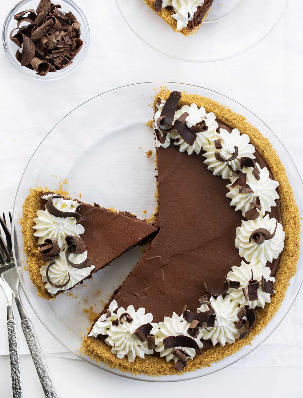 Overhead of a Chocolate Icebox Pie With Two Pieces Removed and Plated Next to the Pie. Dessert, Pie, No Bake Pie, Chocolate Desserts, no Bake Chocolate Desserts, Summer Dessert, Dark Chocolate Dessert, What to Serve to Company for Dessert, recipes, chocolate, chocolate curls, Whipped Cream, i am baker, iambaker.