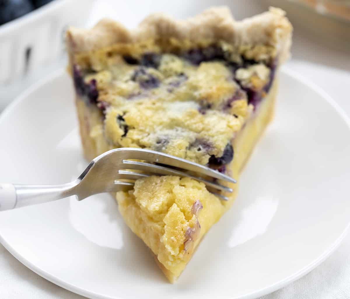 Fork Taking a Bite of Blueberry Buttermilk Pie. Dessert, Baking, Pie, Pie Crust, Best Pie Crust, Buttermilk Pie, Blueberry Pie, Christmas Dessert, Summer Dessert, Old Fashioned Dessert, i am baker, iambaker