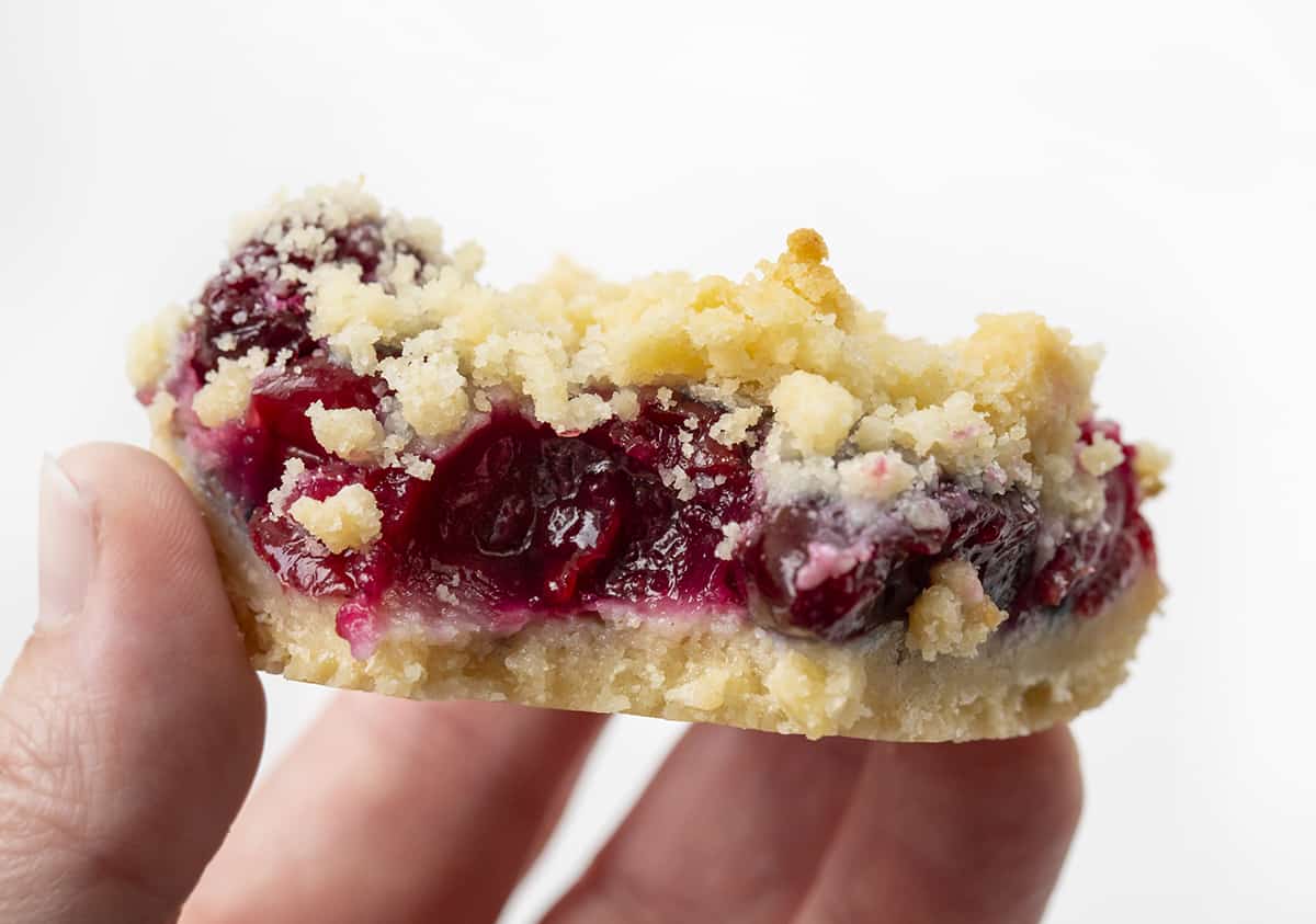 Hand Holding Bit Into Cherry Pie Bars. Dessert, Baking, Bars, Cherry Bars, Cherry Pie Bars, Homemade Cherry Pie Filling, Easy Bars, Real Cherry Desserts, Summer Baking, Winter Baking, Christmas Recipes, i am baker, iambaker.