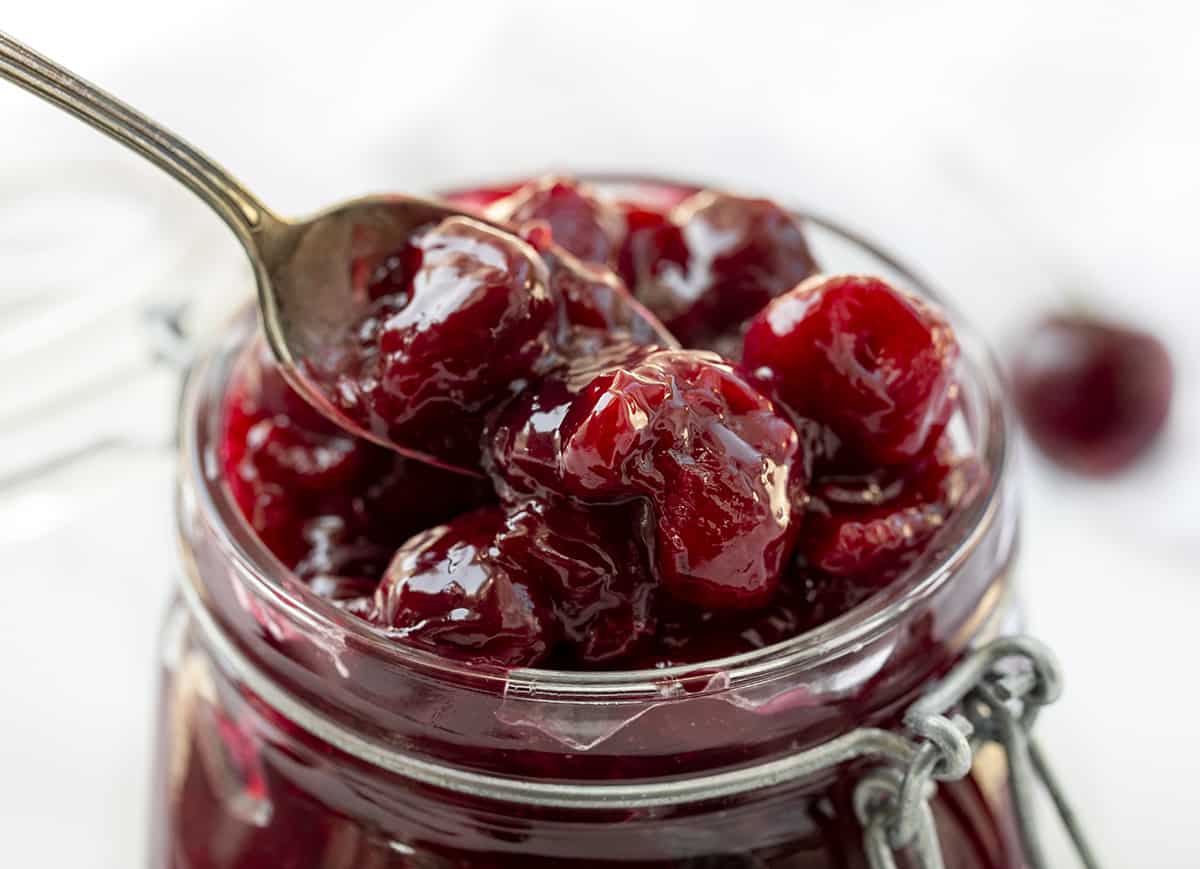 Spooning Cherries out of a Jar of Cherry Pie Filling on White Counter. Cherry Pie Filling, Sweet Cherries, How to Pit Cherries, Cherry Desserts, Dessert, Pie Filling. Homemade Cherry Pie Filling, From Scratch Cherry Pie Filling, Cherry Pie, i am baker, iambaker