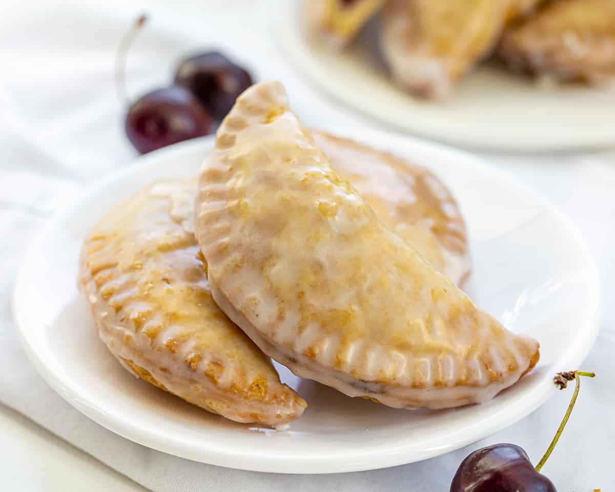 Plate of Cherry Hand Pies with Glaze. Dessert, Snack, Hand Pies, Fried Pies, Fried Hand Pies, Cherry Pies, Air Fryer Cherry Hand Pies, Fried Cherry Hand Pies, Oven Cherry Hand Pies, Cherry Desserts, Baking, Cherry Recipes, Christmas Recipes, Summer Desserts, i am baker, iambaker