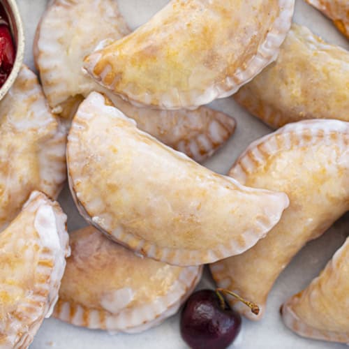 Tray of Cherry Hand Pies with Real Cherry Pie Filling Next to It. Dessert, Snack, Hand Pies, Fried Pies, Fried Hand Pies, Cherry Pies, Air Fryer Cherry Hand Pies, Fried Cherry Hand Pies, Oven Cherry Hand Pies, Cherry Desserts, Baking, Cherry Recipes, Christmas Recipes, Summer Desserts, i am baker, iambaker