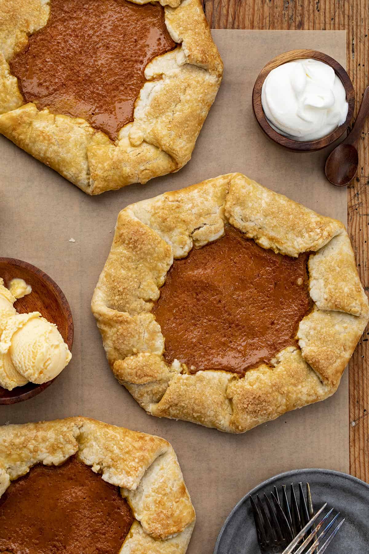 Pumpkin Galettes on a Cutting Board from Overhead with Ice Cream and Whipped Cream. Dessert, Thanksgiving, Pumpkin Pie Galette, Easy Pumpkin Dessert, How to Make Pumpkin Galette, Holiday Desserts, Easy Dessert, Pie Crust, Galette, i am baker, iambaker