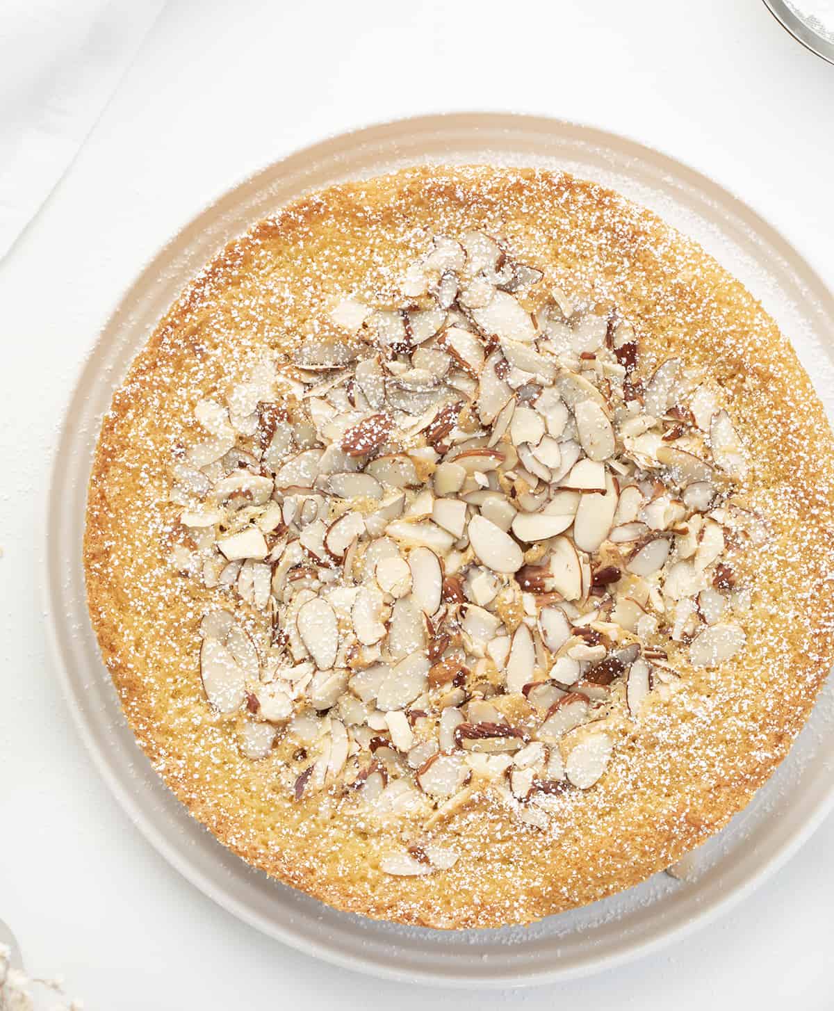 Whole Almond Cake on White Plate Sprinkled with Confectioners Sugar. Almond Cake, French Almond Cake, Moist Almond Cake, How to Make Almond Cake, Almond Cake Recipes, Easy Almond Cake Recipes, Baking, Dessert, Holiday Baking, Christmas Cake, Thanksgiving Cake, i am baker, iambaker