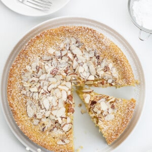 Almond Cake on a White Surface with Plates and Confectioners Sugar and a Slice Removed. Almond Cake, French Almond Cake, Moist Almond Cake, How to Make Almond Cake, Almond Cake Recipes, Easy Almond Cake Recipes, Baking, Dessert, Holiday Baking, Christmas Cake, Thanksgiving Cake, i am baker, iambaker