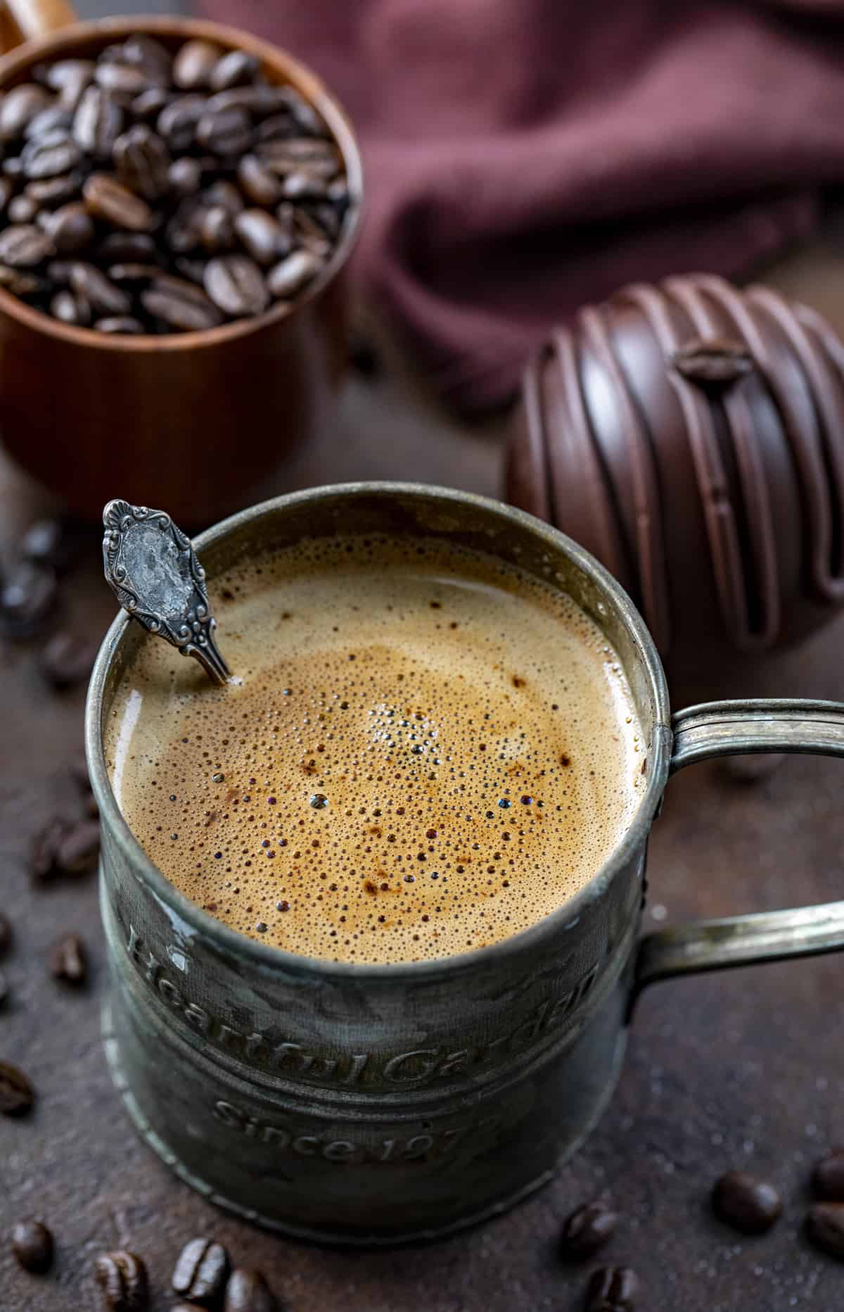 Mug with Mocha Coffee Bomb melted and stirred and Mocha Coffee Bombs Behind it. Hot Cocoa Bombs, Hot Chocolate Bombs, How to Make Hot Chocolate Bombs, Best Chocolate Bomb Flavors, Costco Chocolate Bombs, Hot Chocolate Bombs AllRecipes, How to Store Chocolate Bombs, Hot to Store Hot Cocoa Bombs, How to Store Mocha Coffee Bombs, i am baker, iambaker